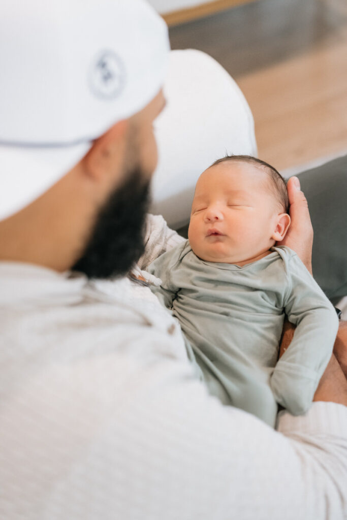 A person sitting on a couch holding their newborn child 