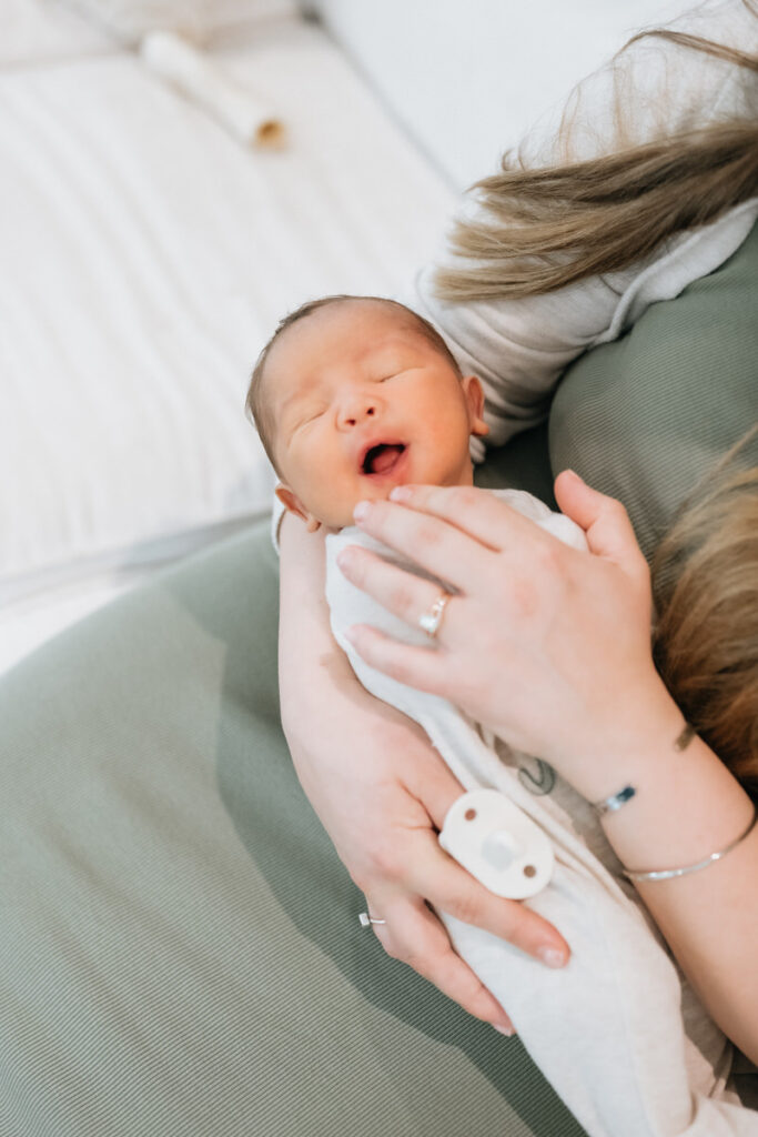 A person holding a newborn as they yawn