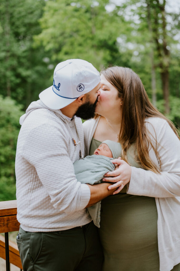 A couple kissing while holding a baby in between them 