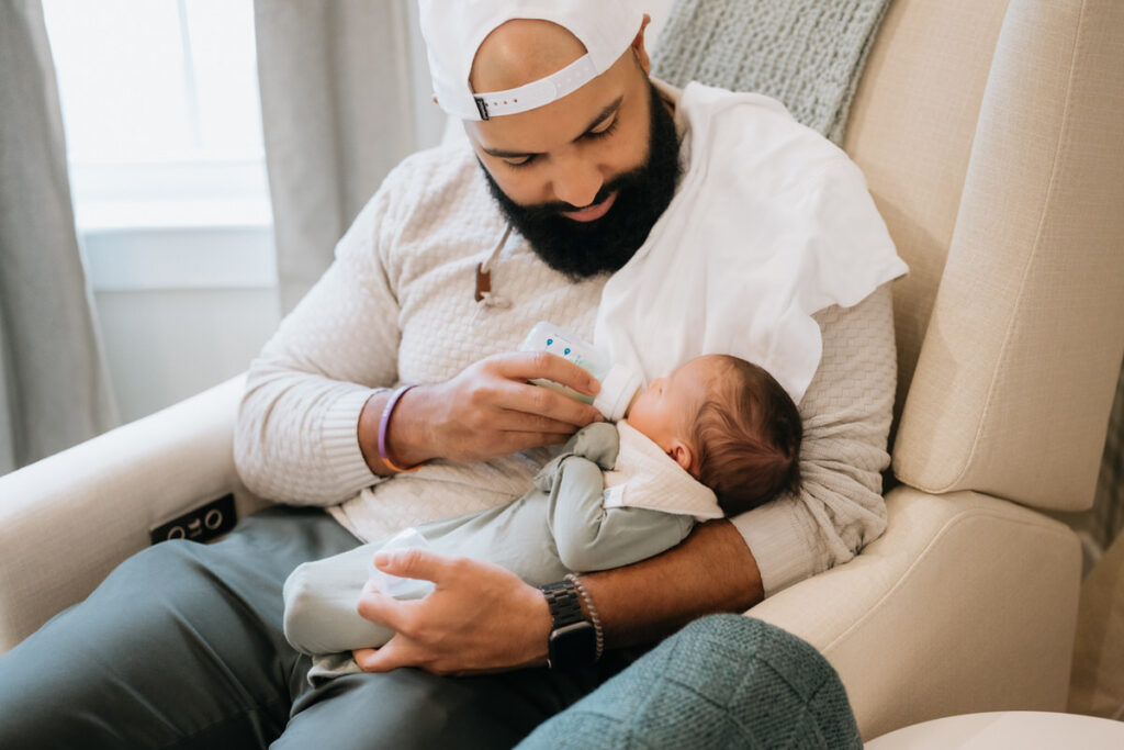 A parent sitting on a rocking chair feeding a newborn 
