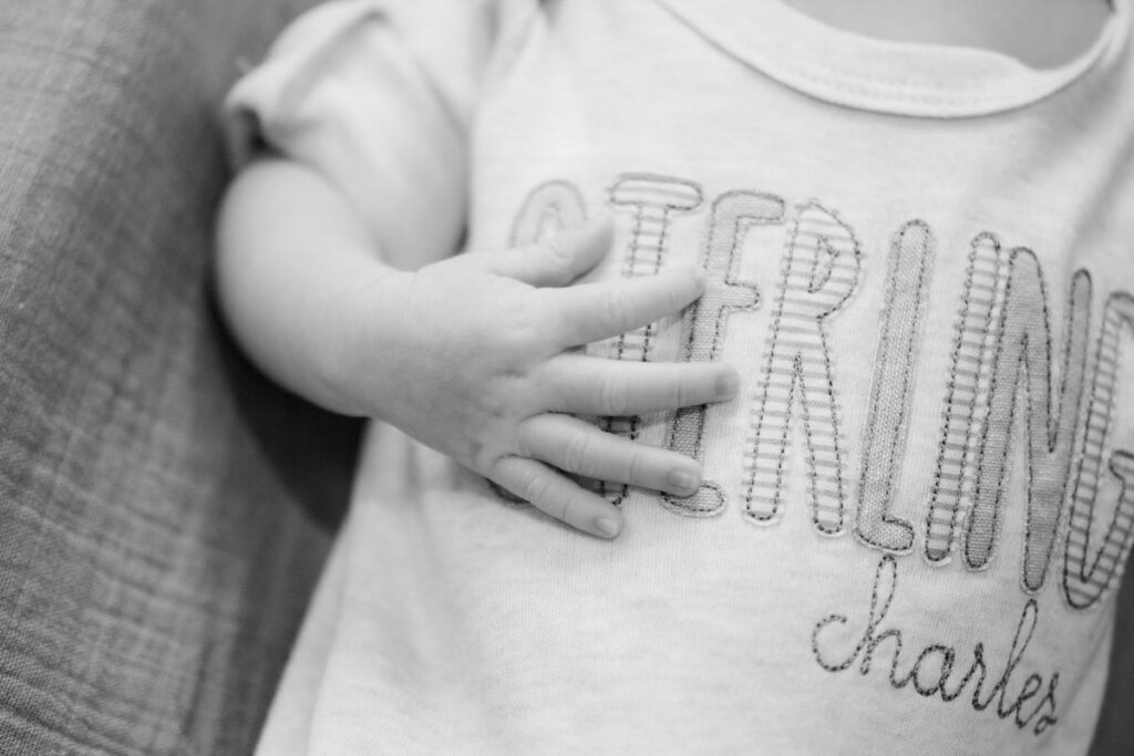 A newborn with a onesie on that says "Sterling Charles" 