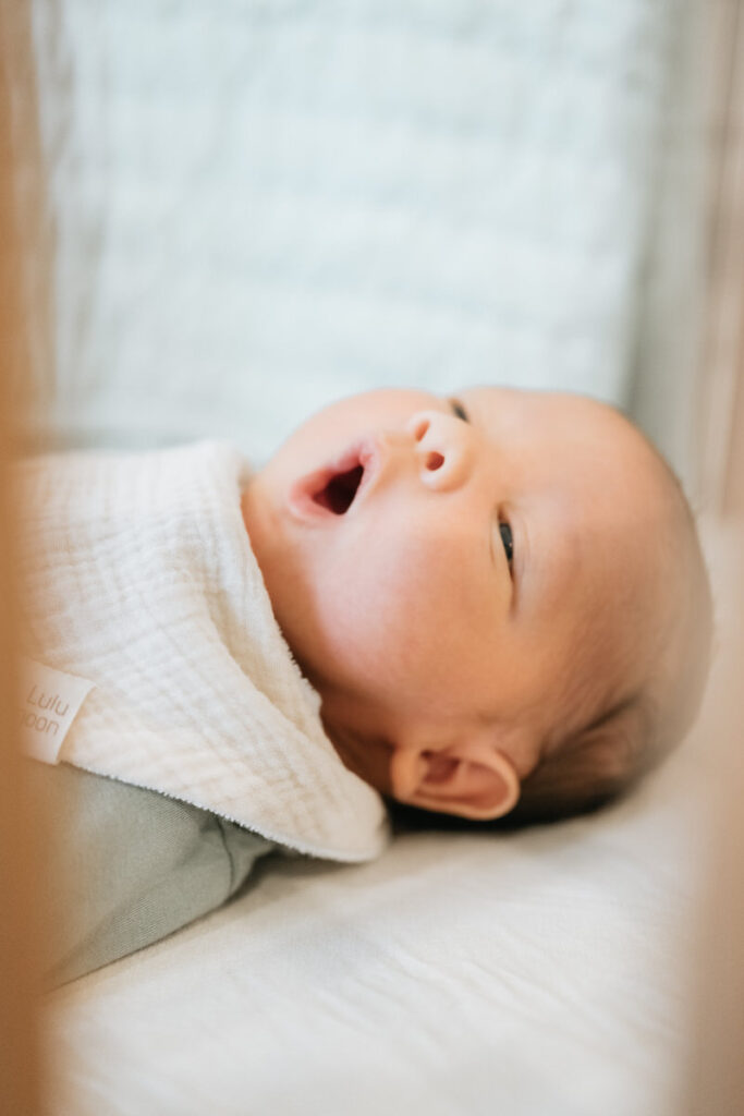 A newborn laying down and yawning 
