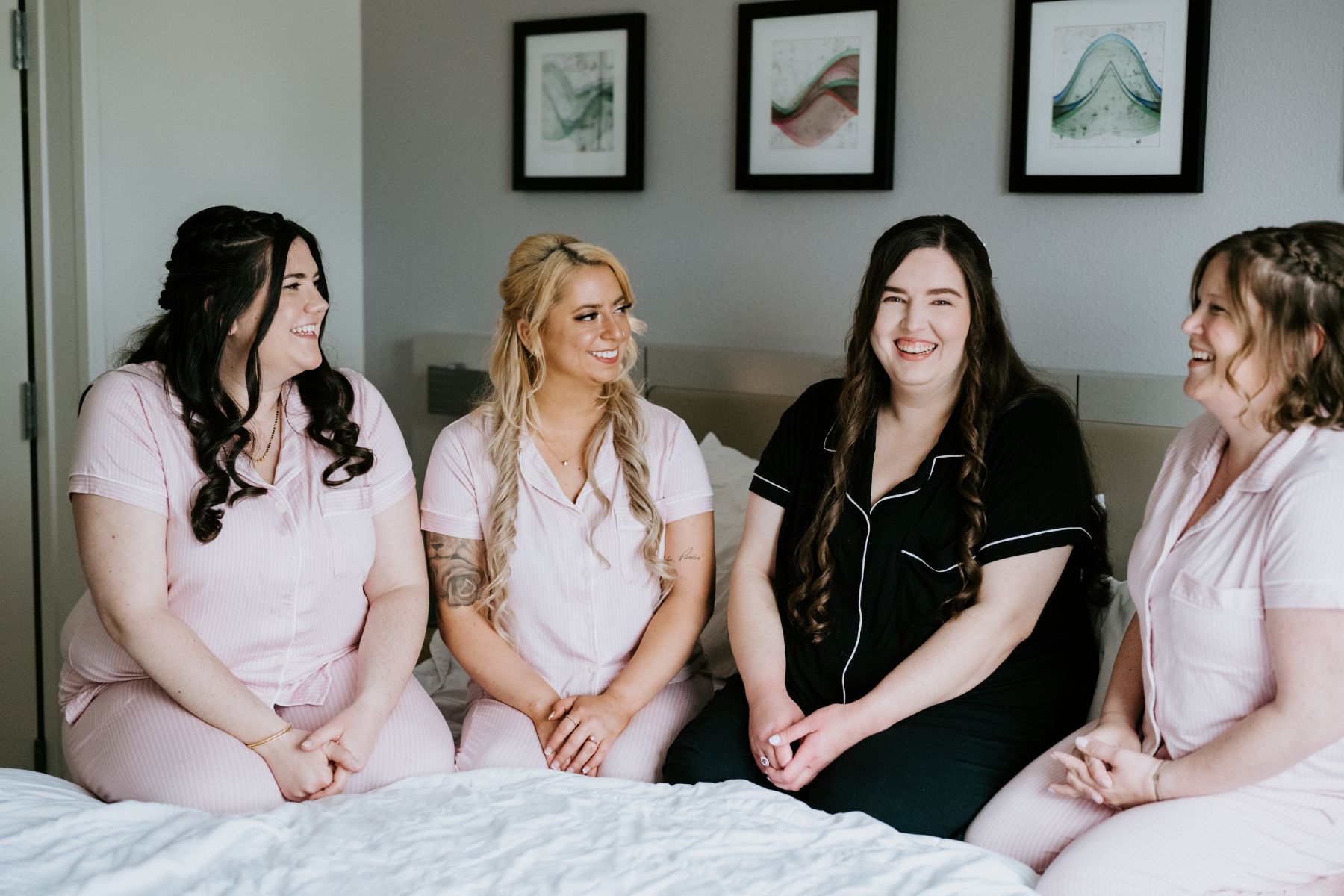 a bridal party sitting in a room weraing matching pajamas and smiling at each other