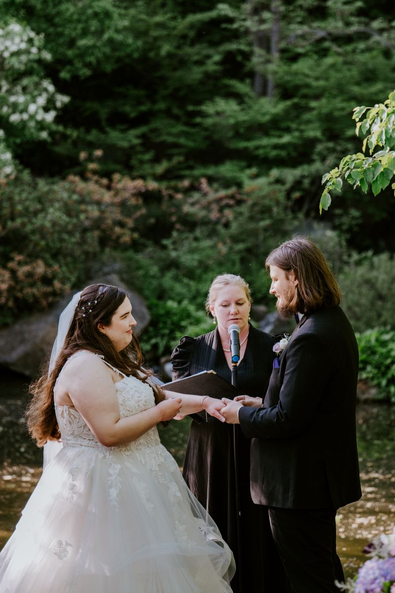 a couple having their wedding ceremony in anderson japanese gardens their officiant is behind them reading from a book